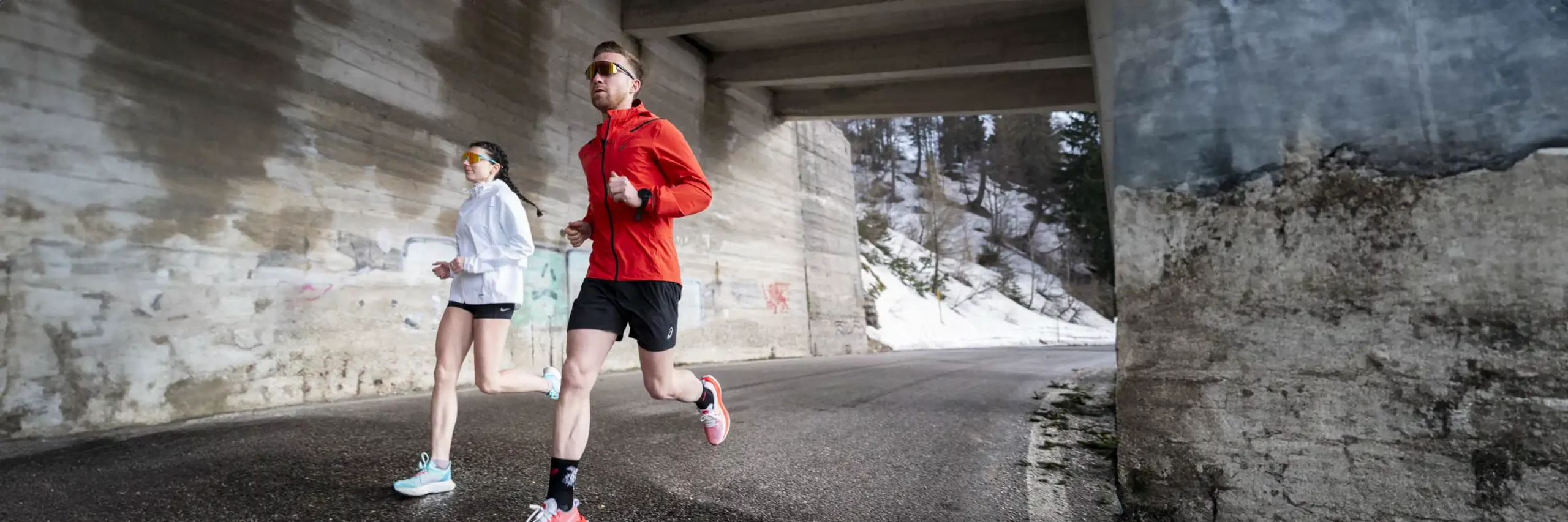 Twee hardlopers met sportbrillen joggen in stedelijke omgeving